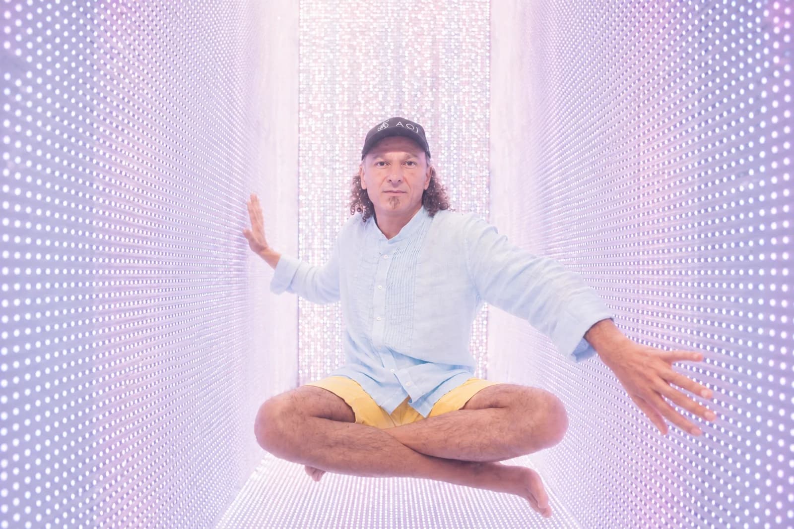 Johny Dar seated cross-legged inside an illuminated AOI Light Chamber